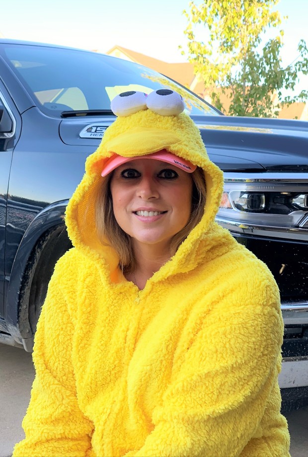 Heather Killebrew in a fuzzy yellow Halloween costume with cartoon eyes on the hood, sitting in front of a black truck in Wentzville, Missouri